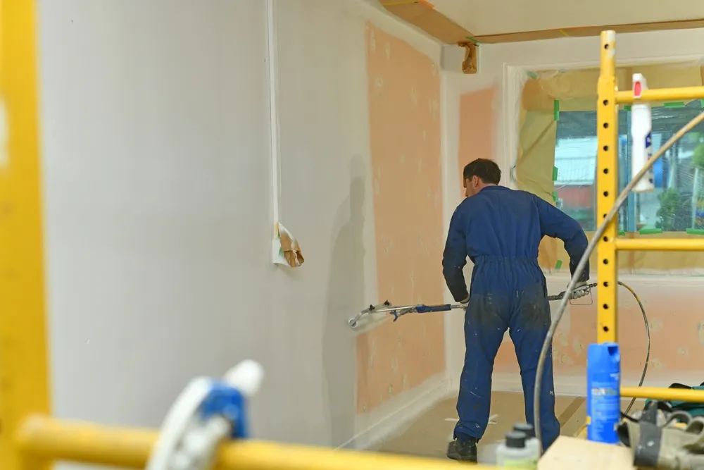 A professional painter from Superior Paint & Remodeling LLC using an extended roller to paint over patched drywall during an interior painting project in Kansas City.